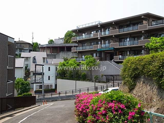 高台にあり、周辺はマンションと一戸建てが混在する緑豊かで閑静な住宅地です。