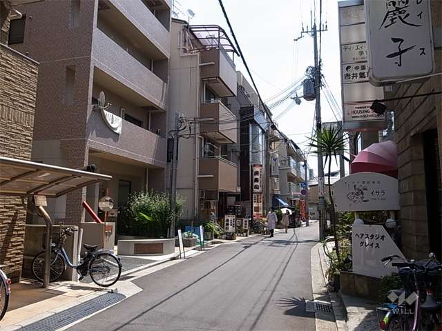 敷地南側の前面道路。周辺は住宅、店舗、事務所などが混在する駅前の街です。