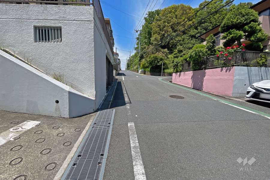 敷地の北東側前面道路（南東側から）。北西方面には緑豊かな『有馬ふるさと公園』が見えます。