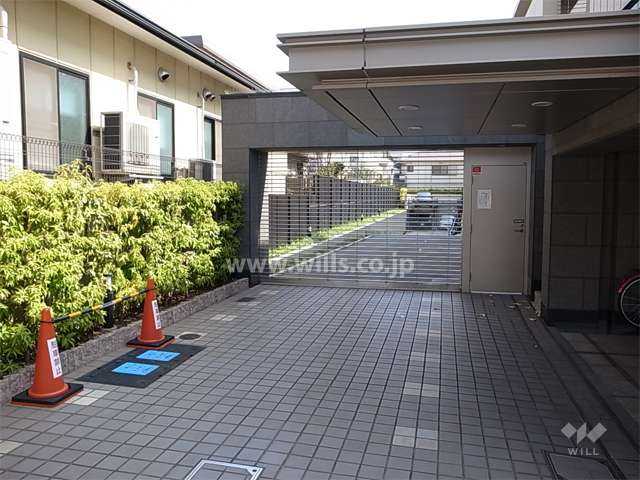 リングシャッター付きの駐車場入り口。エントランスの庇が長く、手前側は車寄せになっています。