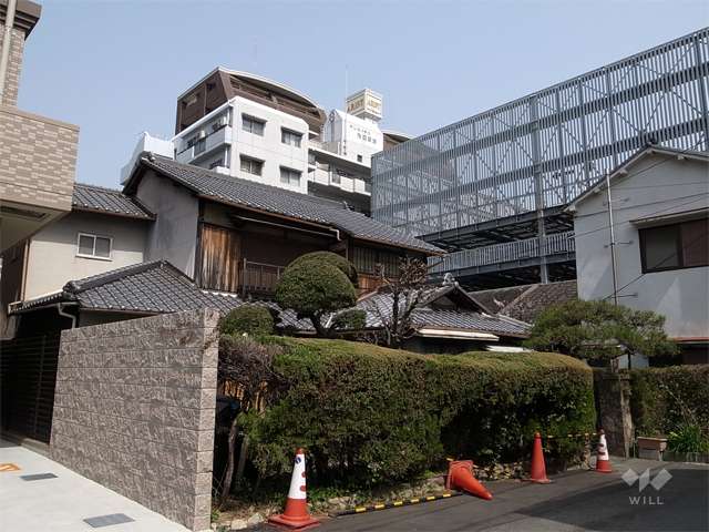 アリスト池田ステーションプレイスの遠景。周辺は駅前の商業地で、住宅や店舗などが混在しています。