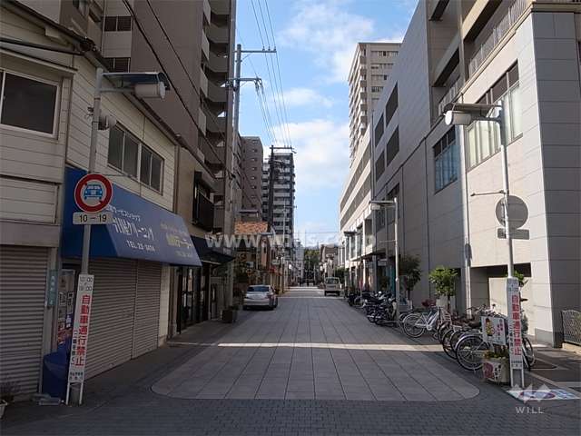 敷地北側の前面道路。向かい側は駅前の商業施設です。
