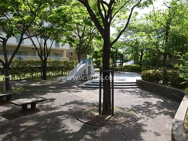 木々が茂り、ベンチや遊具が設置された敷地内の広場