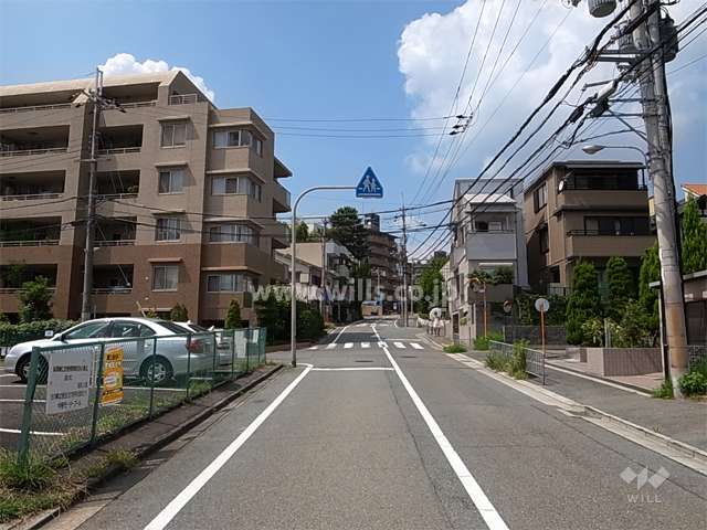 敷地東側の前面道路。ゆるやかな南斜面地の住宅地です。静かで、マンションと一戸建てが混在しています。